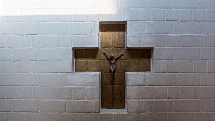 Ein Kruzifix ist in eine Nische einer Ziegelmauer eingelassen