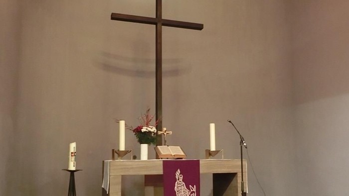 Ein Altar in einer Kirche mit Kreuz, Kerzen und Blumen