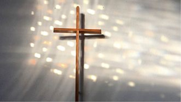 Ein hölzernes Kreuz vor einem hellen, strahlenden Hintergrund