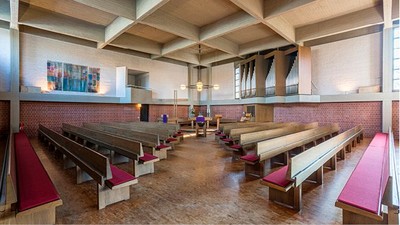Leere Kirche mit Holzbänken und farbenfrohem Glasfenster