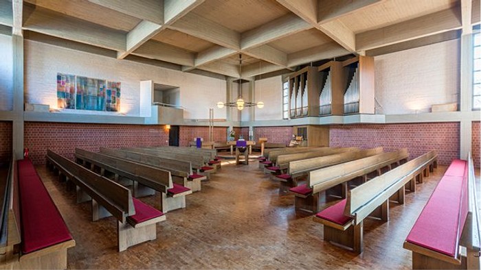 Leere Kirche mit Holzbänken und farbenfrohem Glasfenster