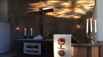 Ein Kirchenaltar mit Kreuz, Kerzen und Kelch-Tuch