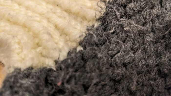 Nahaufnahme von weiß-grauer gestrickter Stofffläche.