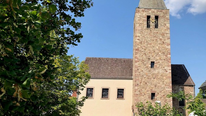 Kirche mit hohem Turm und daneben geparktem Auto.