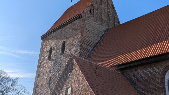 Alte Kirche mit hohem Turm und rotem Dach bei klarem Himmel