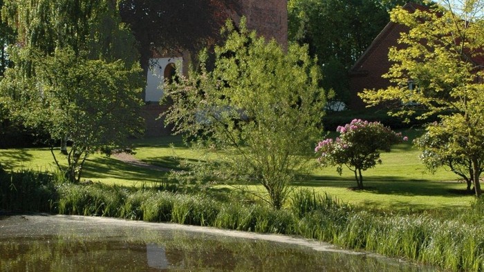 En rolig park med en lille sø og et historisk tårn i baggrunden