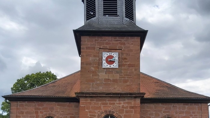 Rotes Backsteingebäude mit einem Turm und Rundbogenfenstern.