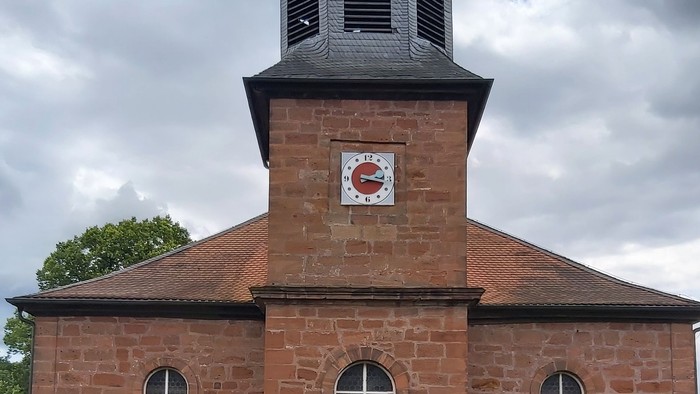 Rotes Backsteingebäude mit einem Turm und Rundbogenfenstern.