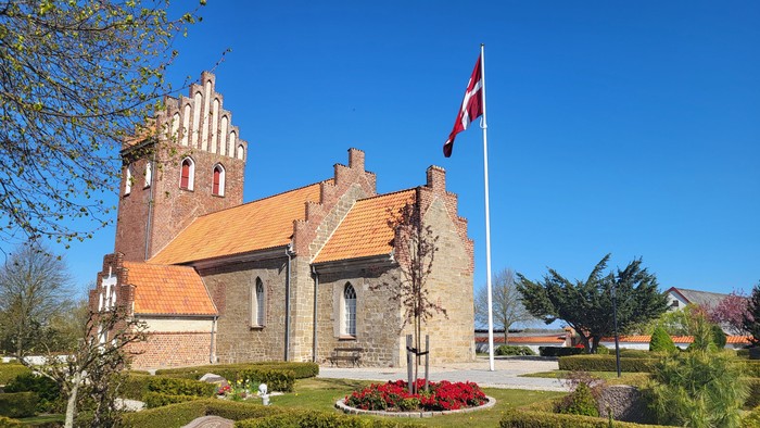 Kirke med rødt tag og dansk flag ved indgangen