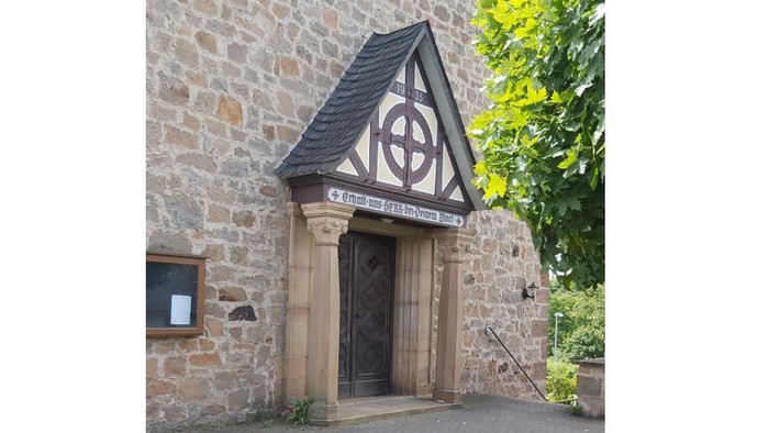 Steingebäude mit Holztür und dreieckigem Dach mit keltischem Design.