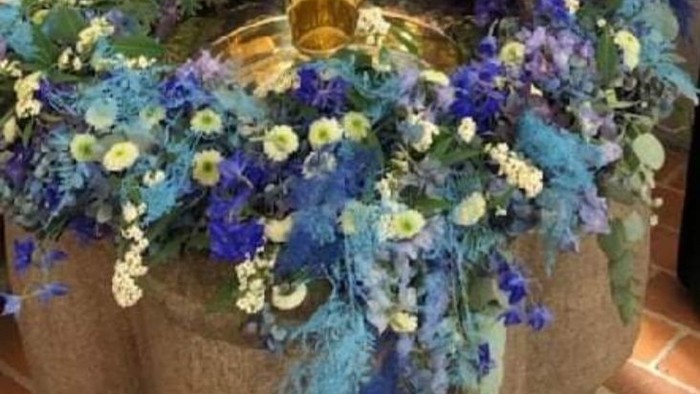 Stort blomsterarrangement med blå og hvide blomster omkring gyldne vaser