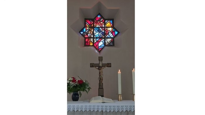 Altar mit Kruzifix, Kerzen und Buntglasfenster