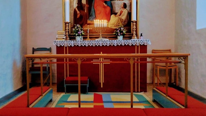 Alter i kirke med lysede lysstaker foran