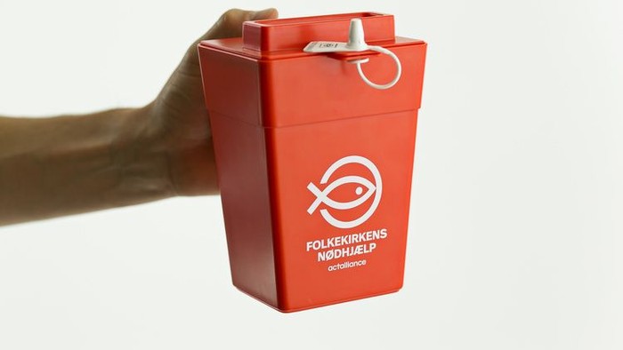 En hånd holder en rød affaldsbeholder med 