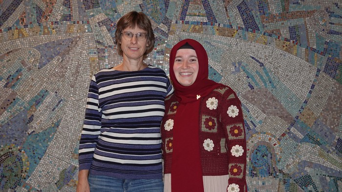 Zwei Frauen stehen vor einer bunten Wand.