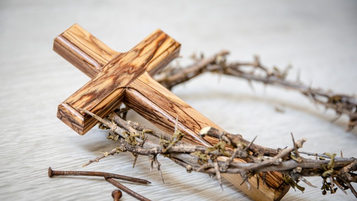 Holzkreuz und Dornenkrone auf einem Holztisch