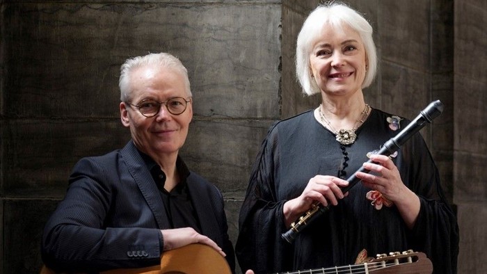 To musikere poser sammen, den ene spiller på en klassisk guitar, og den anden holder en fløjte.