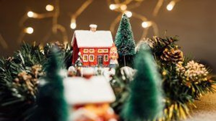 Miniature julelandsby med hus og træer, pyntet med lys og krans.