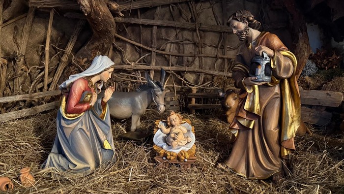 Eine Krippe, die Maria, Josef, das Jesuskind und einen Ochsen in einer ländlichen Stallkulisse darstellt.