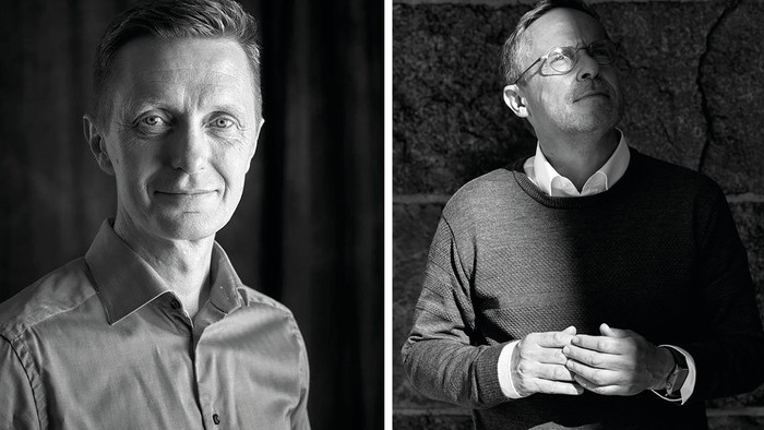 To mænd i professionelt tøj fotograferet i kontrasterende sort-hvid belysning.