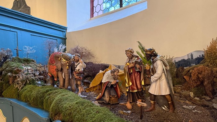 Eine detaillierte Weihnachtskrippe, die die Geburt Jesu mit Hirten, Tieren und Figuren in einer ländlichen Umgebung darstellt.