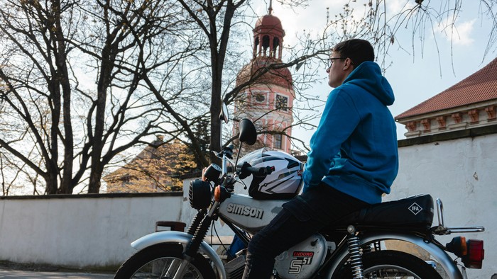 Ein Mann fährt mit einem Motorrad in der Nähe einer Kirche.