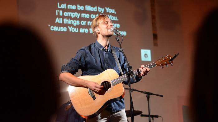 En ung mand spiller guitar og synger på en scene
