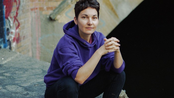 Frau in lila Kapuzenpulli sitzt auf Betonstufen.