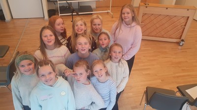 En gruppe af glade børn og unge piger i en indendørs lokalitet