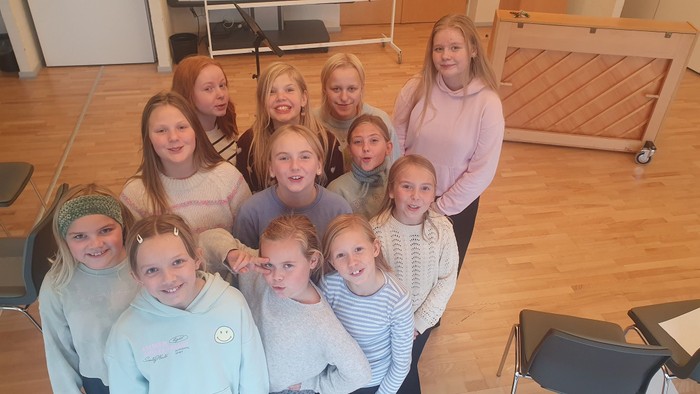 En gruppe af glade børn og unge piger i en indendørs lokalitet