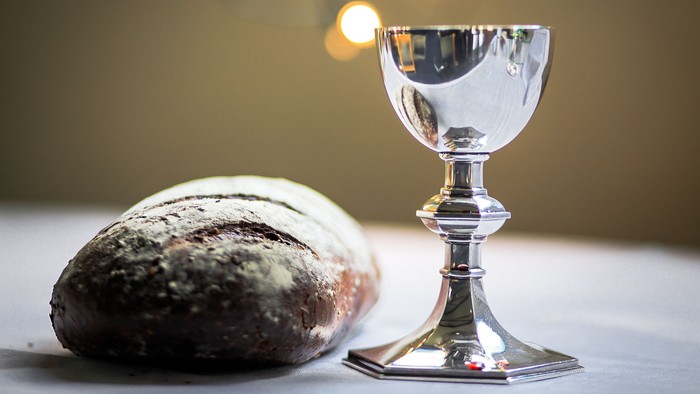 En sølv kalk og et brød på en hvid tabledeklædning