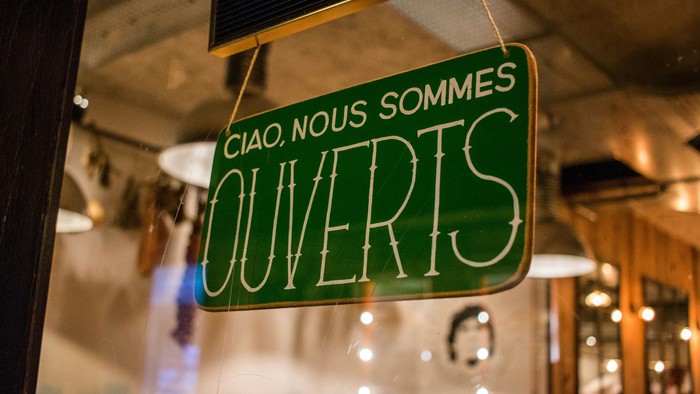 Grøn skilt med fransk tekst hænger i vinduesramme