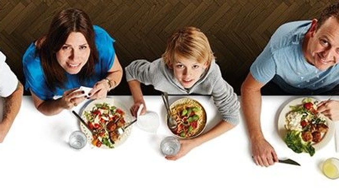 En gruppe af mennesker sidder sammen og spiser pizza.