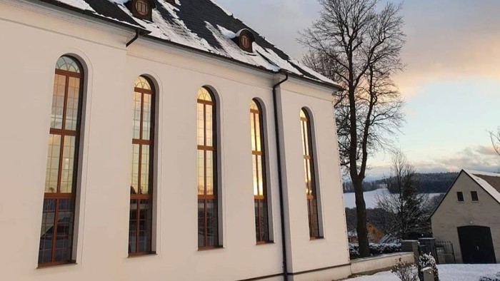 Weiße Kirche im Schnee mit hohem Turm und blauen Himmel