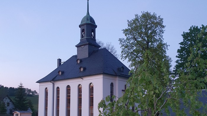Kirche mit Friedhof und Bäumen im Hintergrund