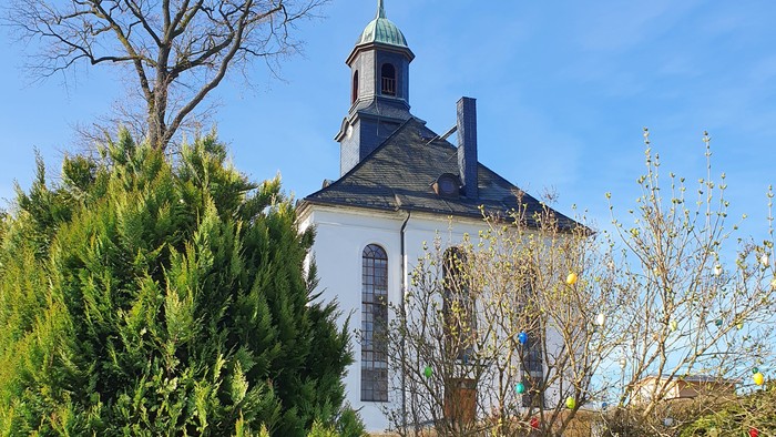 Weißes Kirchgebäude mit blauen Dächern und grünem Garten