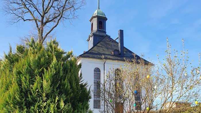 Weißes Kirchgebäude mit blauen Dächern und grünem Garten