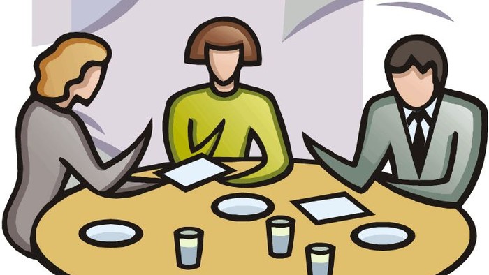 Tre personer sidder ved et bord og diskuterer.