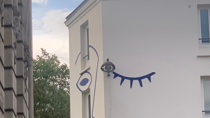 En blå kattefigur på væggen af et hvidt hus.