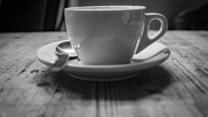 Eine Tasse Kaffee auf einem Unterteller mit einem Löffel