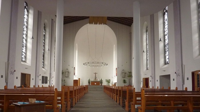 Leere Kirche mit Holzbänken und hohem Gewölbe