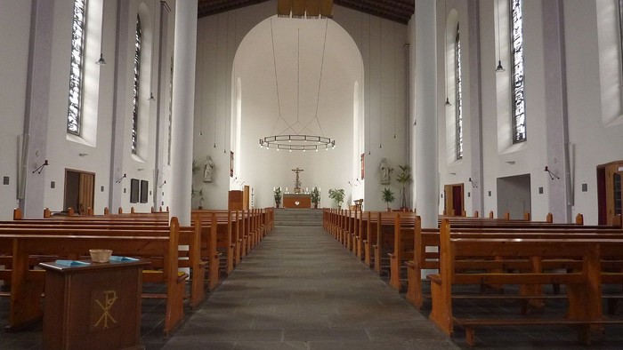 Leere Kirche mit Holzbänken und hohem Gewölbe
