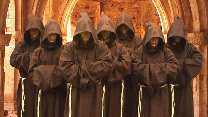 Eine Gruppe von Mönchen in braunen Kutten steht in einer Kirche