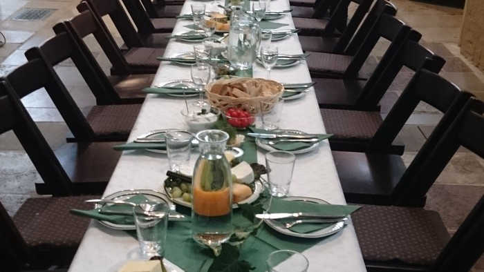 Ein langer Tisch mit weißen Tischtüchern, grünen Servietten und Gläsern, bereit für ein Festmahl