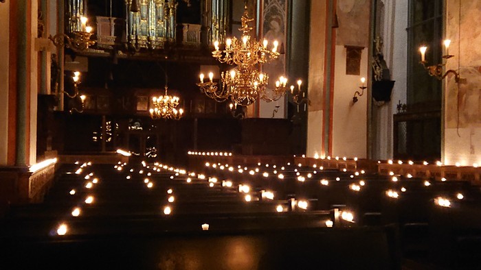 Kirchliche Innenansicht mit vielen Kerzen und Kronleuchtern