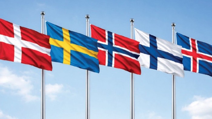 Fem nationale flag fra de nordiske lande, der vajer mod en klar blå himmel.
