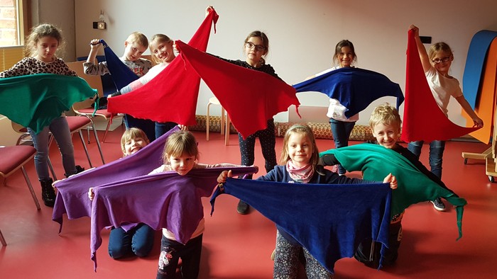 Kinder spielen mit bunten Tüchern in einem Raum