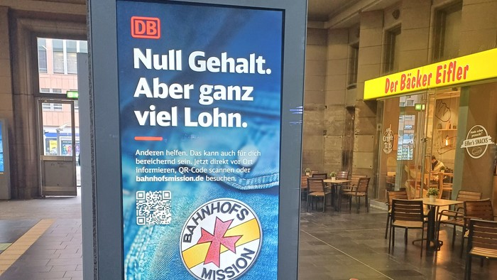 Öffentliche Verkehrsmittelwerbung für ein kalorienfreies Getränk mit hohem Wert, mit einem Missionslogo und QR-Code.
