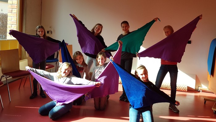 Kinder posieren mit bunten Tüchern in einem Raum