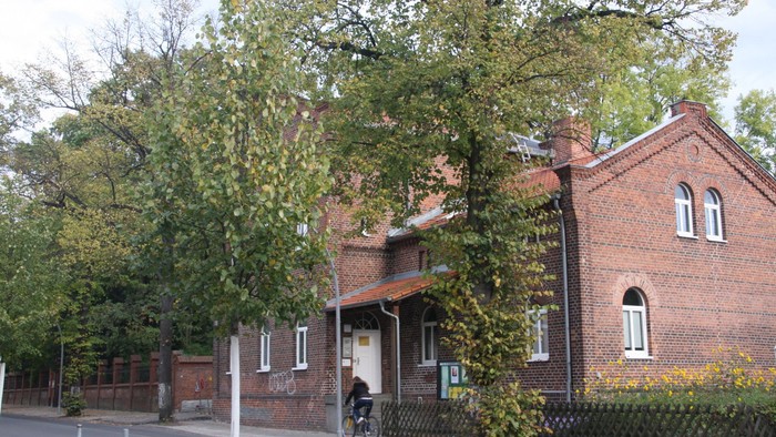 Ein rotes Backsteingebäude mit einem Fahrrad davor und Bäumen daneben